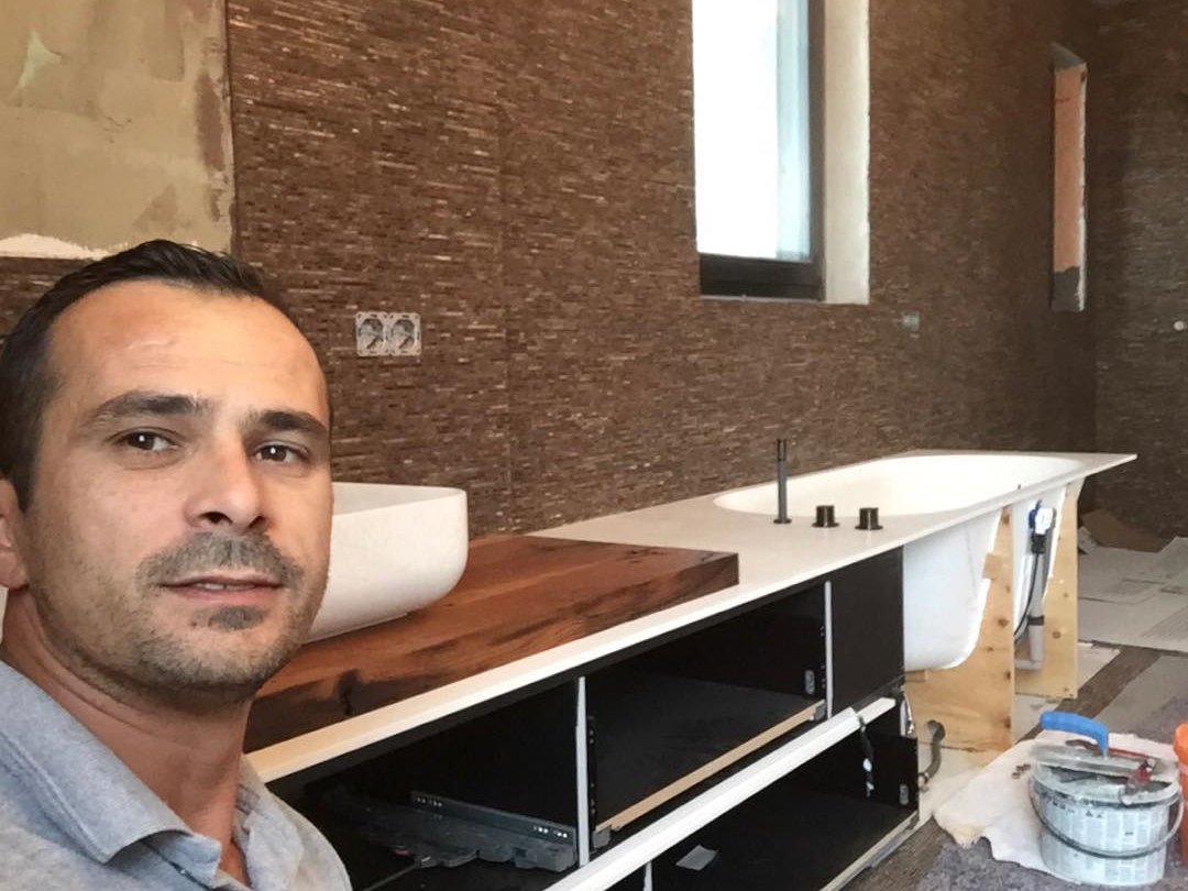 Suad Radoniqi auf einer Baustelle, im Hintergrund ein Bad im Ausbau